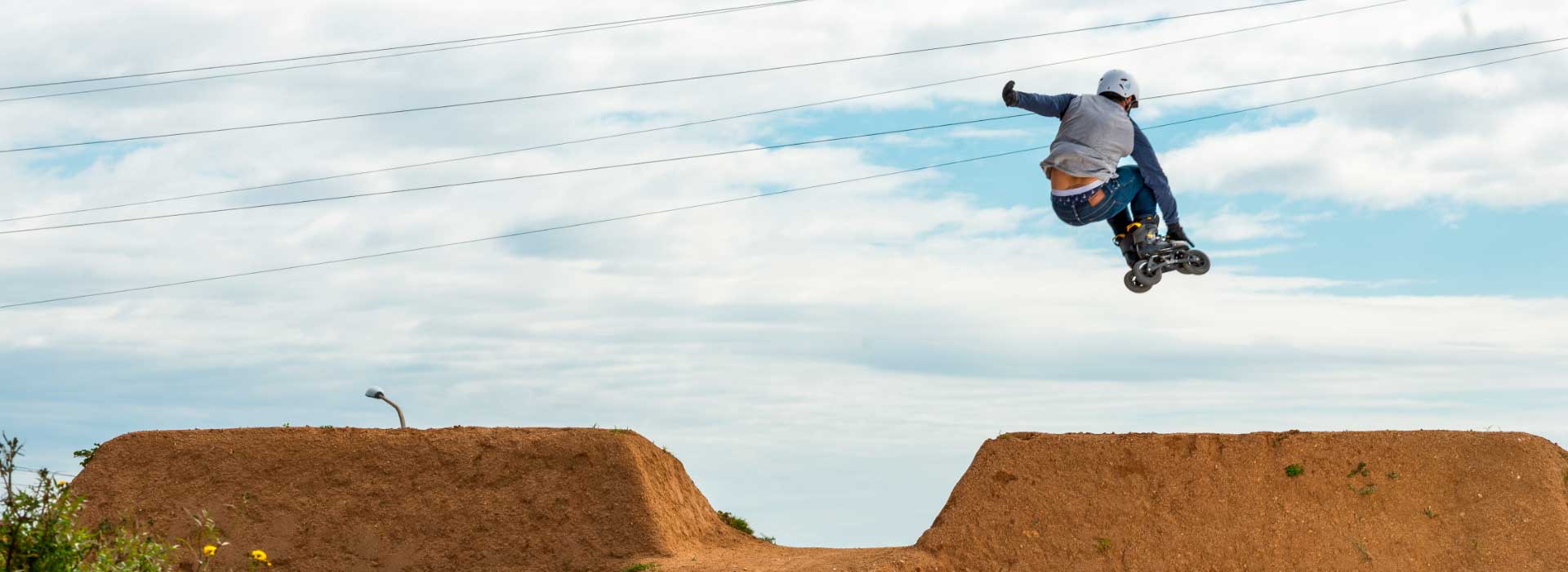 A person on Extreme SUV inline skates launches into the air on a dirt course