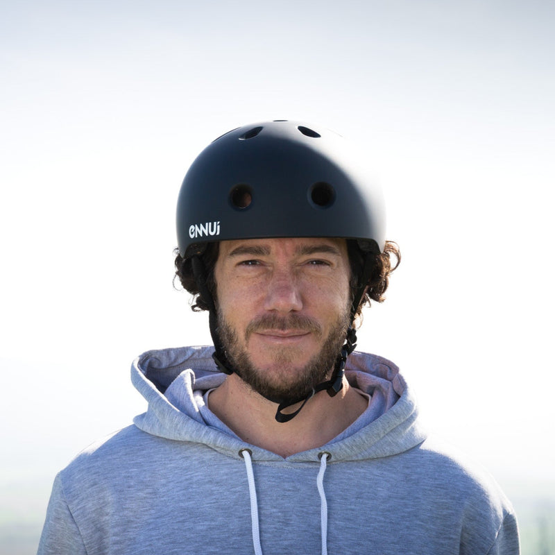 Man wearing a black helmet and blue hoodie with a brand logo, standing outdoors.