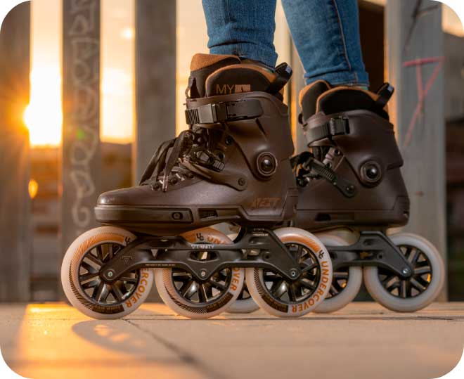 Close-up image of a pair of brown Powerslide Next inline skates with a sunset in the background